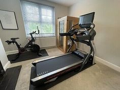 a home gym with treadmills and exercise equipment in the room, including a laptop computer