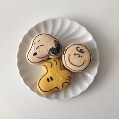 three cookies decorated to look like cartoon characters on a white plate with yellow icing