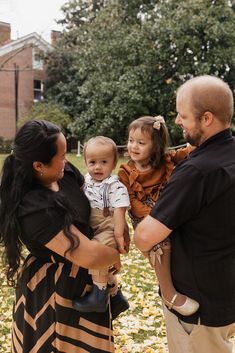 a man and woman holding a baby in their arms while standing next to each other