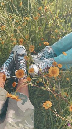 a person standing in the grass with their feet up on some daisies and flowers