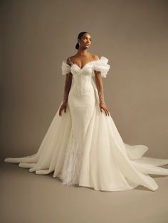 a woman in a wedding dress posing for the camera with her hands on her hips