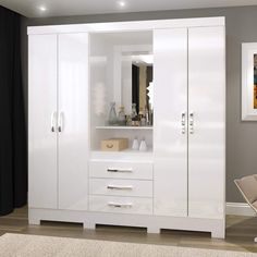 a white armoire in a living room next to a chair