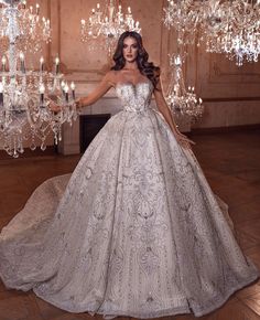 a woman in a wedding dress standing next to a chandelier