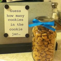 a jar filled with cookies sitting on top of a counter next to a sign that says guess how many cookies in the cookie jar