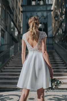 the back of a woman's dress as she walks up steps in front of a building