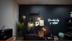 a room with a desk, shelves and a television on the wall in front of it