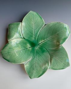 a green leaf shaped dish sitting on top of a table