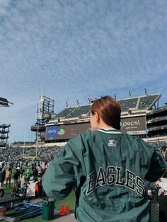 a woman in a baseball uniform is standing on the sidelines at a football game