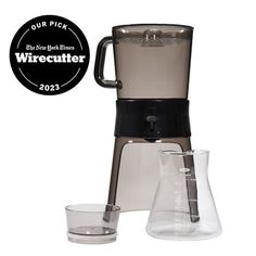 a black and gray coffee maker with two glasses next to it on a white background