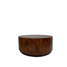 a round wooden table sitting on top of a white wall