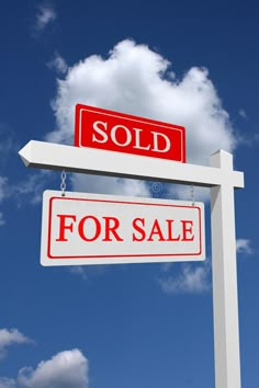 a sold sign and for sale sign in front of a blue sky with white clouds