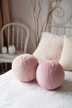 two pink pillows sitting on top of a white bed