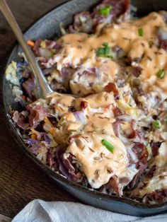 a skillet filled with coleslaw and dressing on top of a wooden table