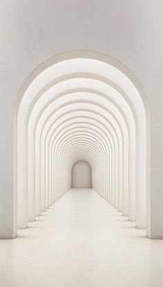 an empty hallway with white walls and arches leading to the light at the end is shown