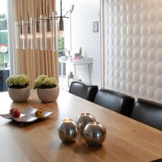 a dining room table with black leather chairs and vases filled with flowers on it