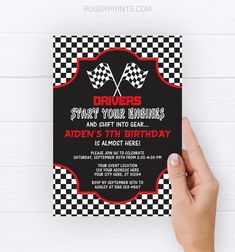 a hand holding up a black and white checkered birthday card with the words drivers, start your engines and shift into gear