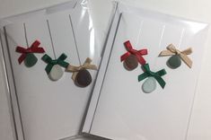 two christmas cards with bows and buttons on them, one has a coin in the middle