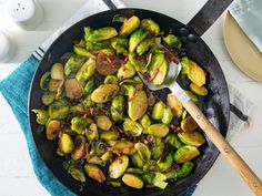 brussel sprouts in a skillet with a wooden spoon on the side