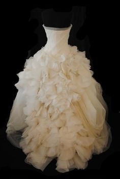 a white wedding dress on display in front of a black background