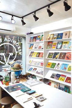 the interior of a book store with many books on shelves and lamps hanging from the ceiling