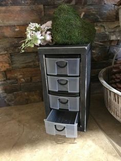 an old dresser has moss growing on it's drawers and is next to a bucket with flowers