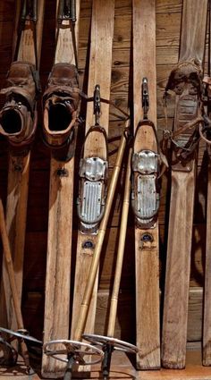 several pairs of skis are lined up against a wooden wall with other skis in the background