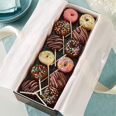 a box filled with lots of different flavored donuts on top of a table