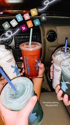 two people are holding drinks in their hands while sitting in the backseat of a car