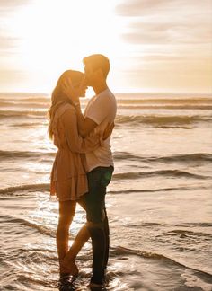 a couple kissing in the ocean at sunset