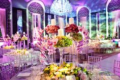 an elaborately decorated dining room with chandeliers and flowers on the tables in front of them