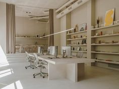 an office with two desks and chairs in front of bookshelves on the wall