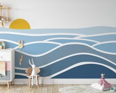 a child's room decorated in blue and white with waves painted on the wall