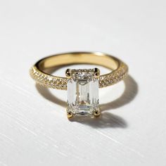 an emerald cut diamond ring with pave set shoulders