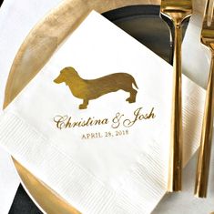 a white napkin with a gold dachshund on it and a black plate