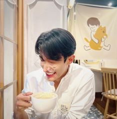 a young man is eating cereal out of a bowl