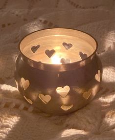 a candle that is sitting on a blanket with hearts cut out in the middle of it