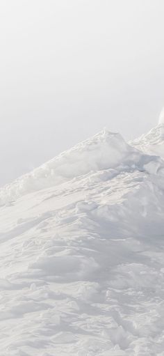 a man riding skis down the side of a snow covered slope on top of a mountain