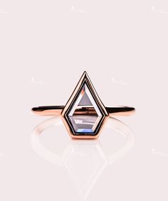 a rose gold ring with a blue topazte stone in the center, on a white background