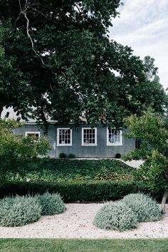 a gray house surrounded by trees and bushes