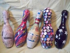 three bowling pins, one with buttons and the other with stars on them are lined up against a white sheet