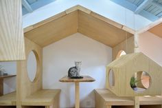 a cat sitting on top of a wooden shelf next to a small table and chairs