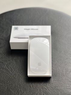 an apple mouse sitting on top of a table next to a white box with the lid open