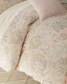 the comforter is made up with pink and beige floral designs on it, along with two pillows