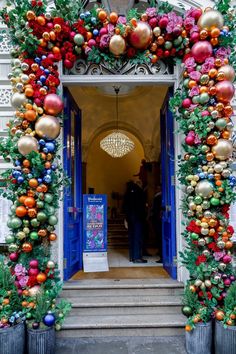 an entrance to a building decorated with christmas ornaments and greenery on the front door