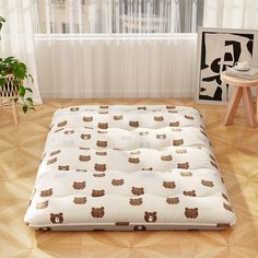 a white and brown bear print futon mattress in a room with wood flooring