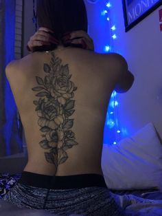 the back of a woman's body with flowers tattooed on her upper and lower back