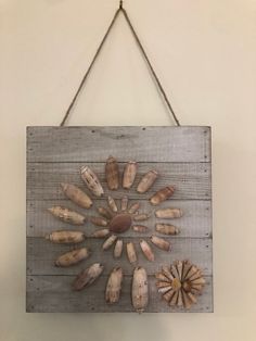 a wooden sign with shells hanging from it's side on a wall next to a string