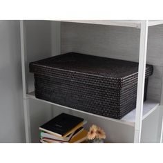 a wicker basket sitting on top of a book shelf next to a vase with flowers