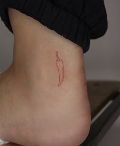 a small red chili pepper tattoo on the side of a woman's lower leg