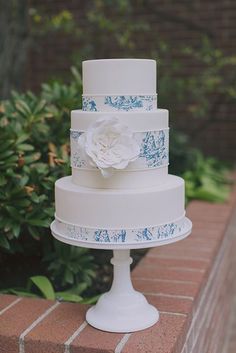 a white and blue wedding cake sitting on top of a brick wall